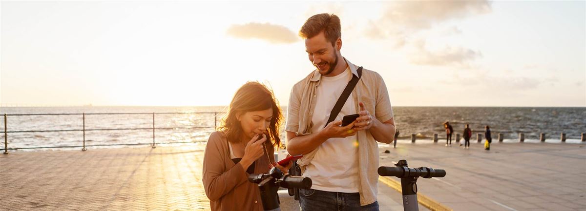 Couple with electric push scooters on pier