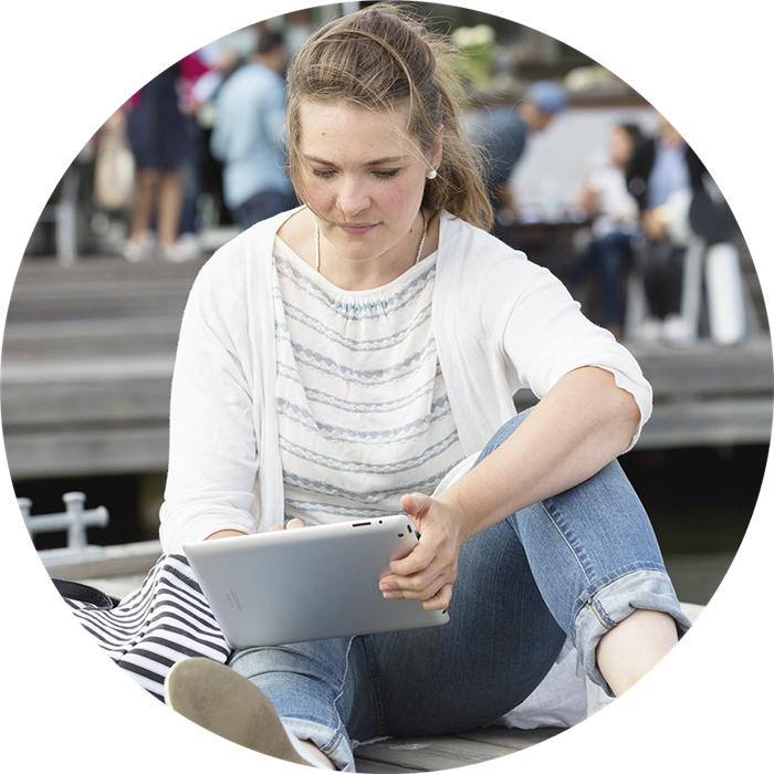 Tjej som sitter på bryggan och tittar i sin laptop