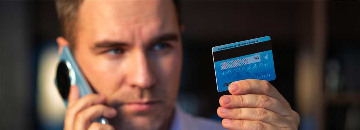 Man on phone looking at bank card
