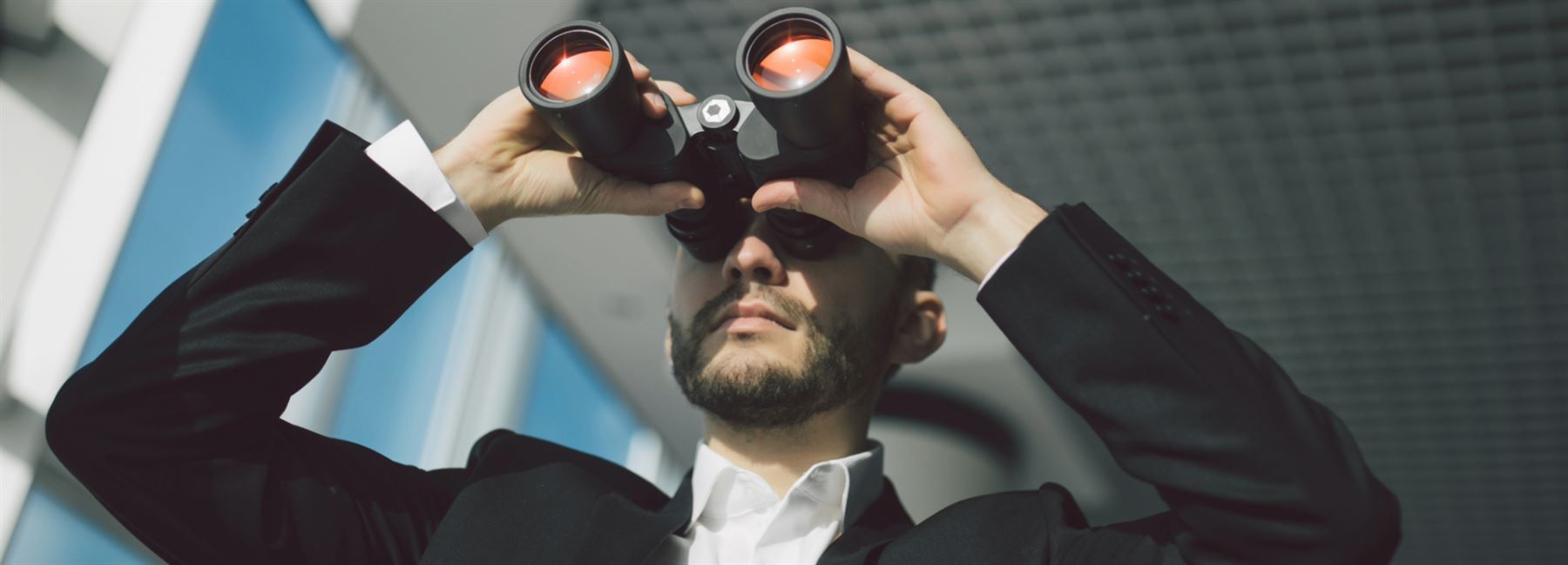 Man in suit looking through binoculars