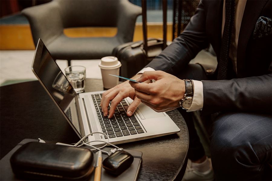 Man looking at bank card while typing on laptop
