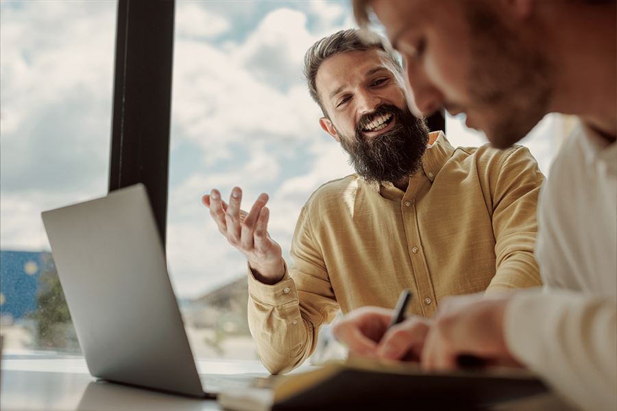 Two men talking with a laptop