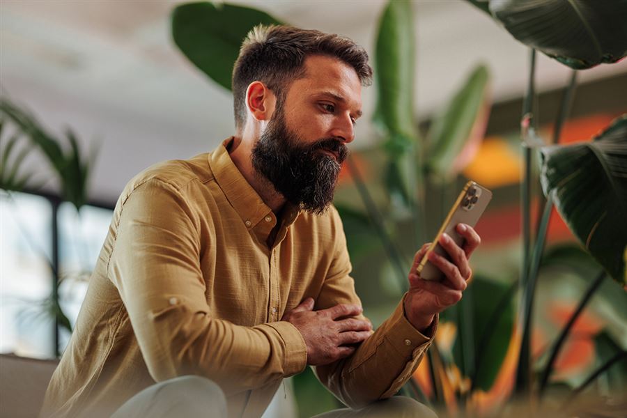 Man with beard looking at mobile phone